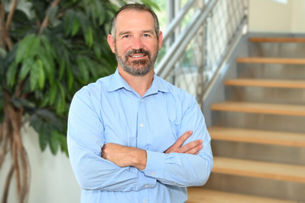 a man with his arms crossed standing in front of stairs