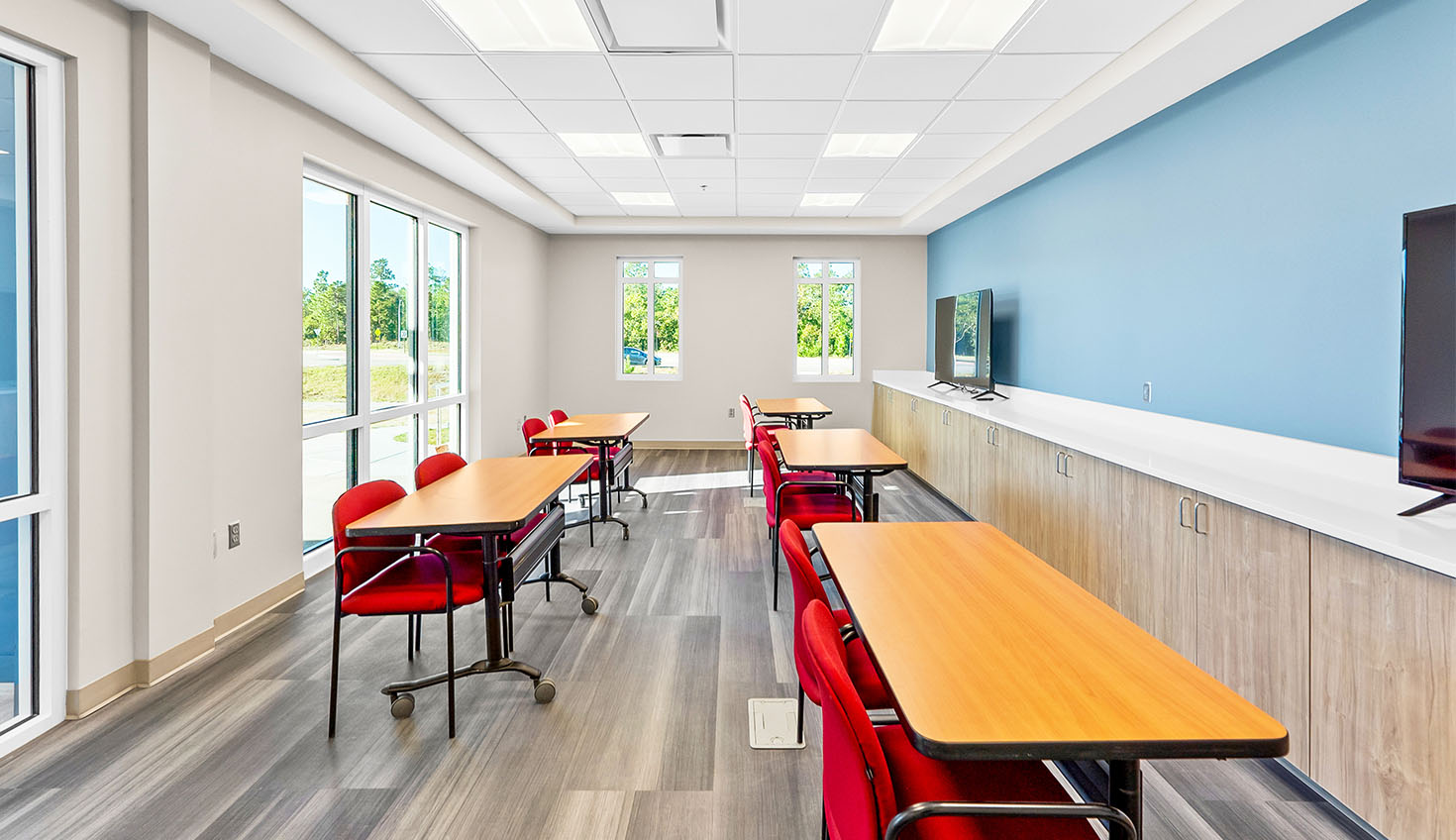 a room with tables, chairs, and a flat screen tv