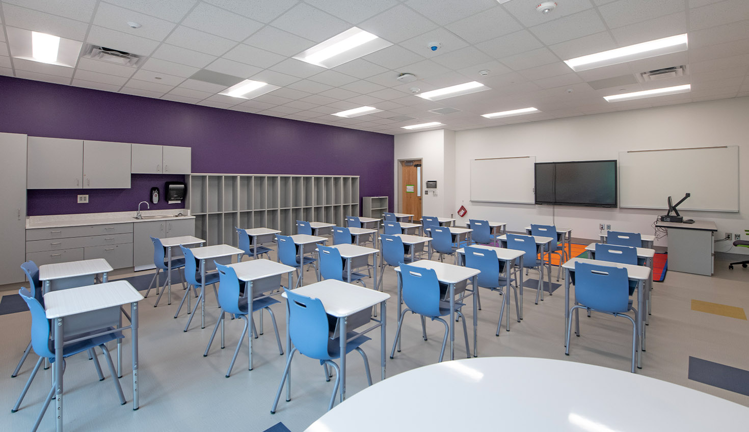 a classroom with desks and chairs and a projector screen