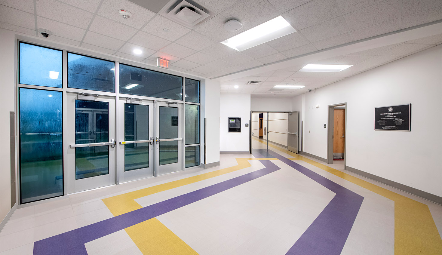 an empty hallway with a large window and colorful carpet
