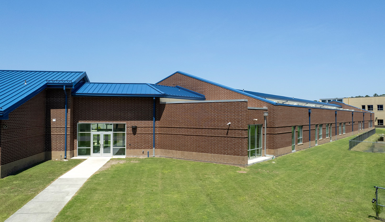 a brick building with a blue roof on a grassy field