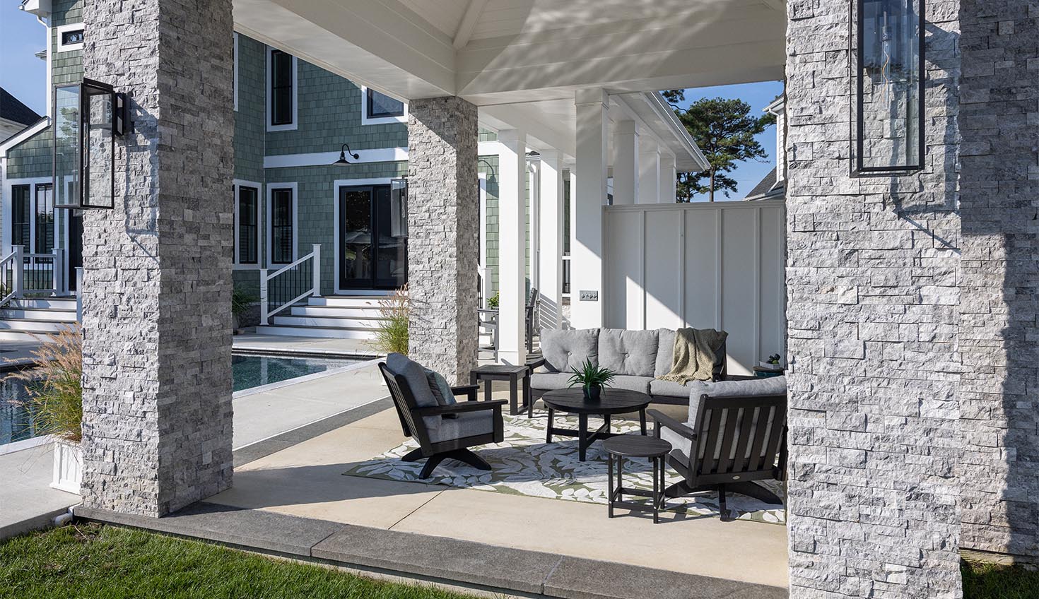 a covered patio with chairs and tables next to a pool