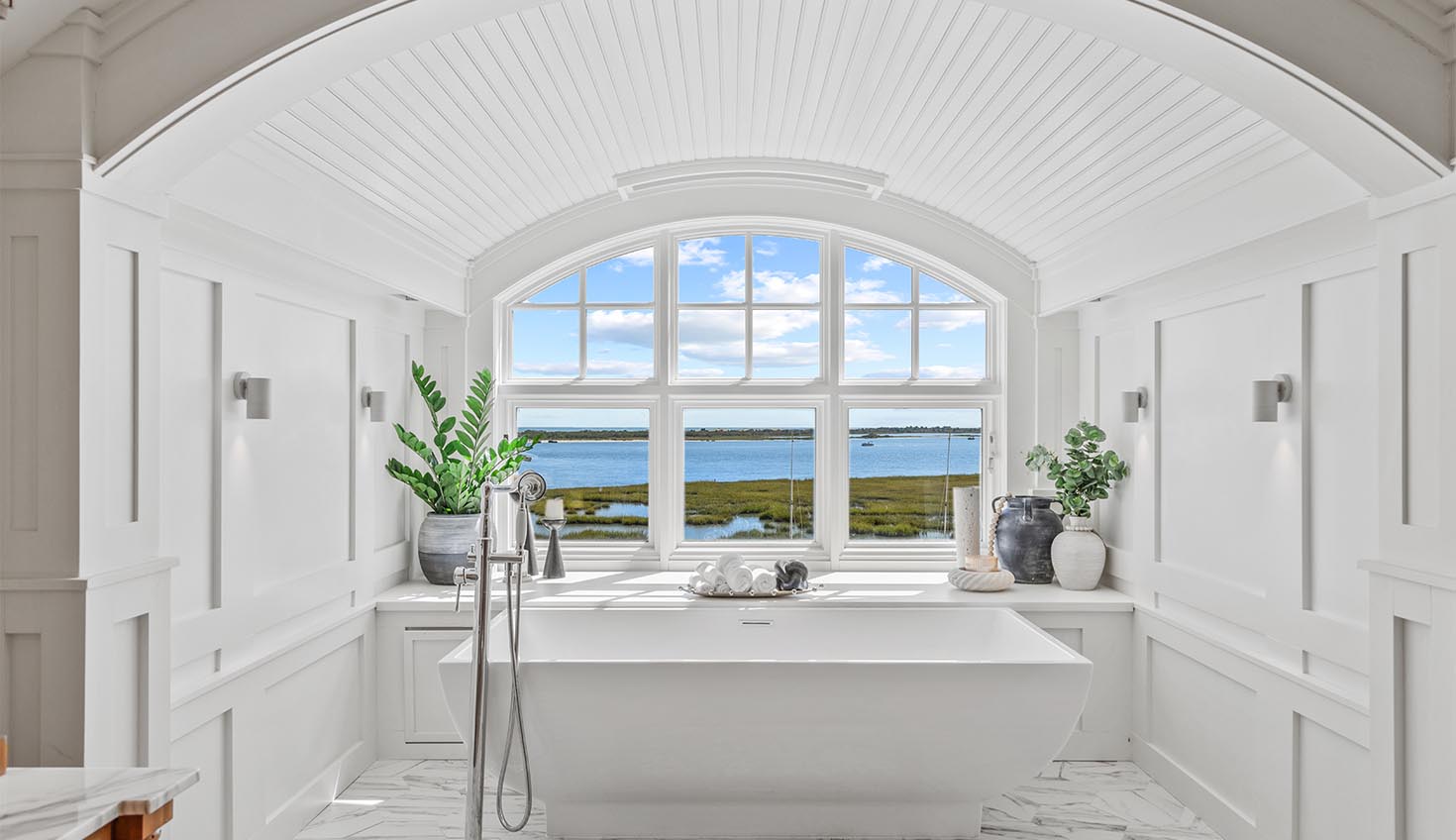 a white bathroom with a large window and a tub