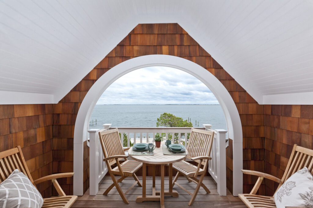 a porch with a table and chairs and a view of the ocean