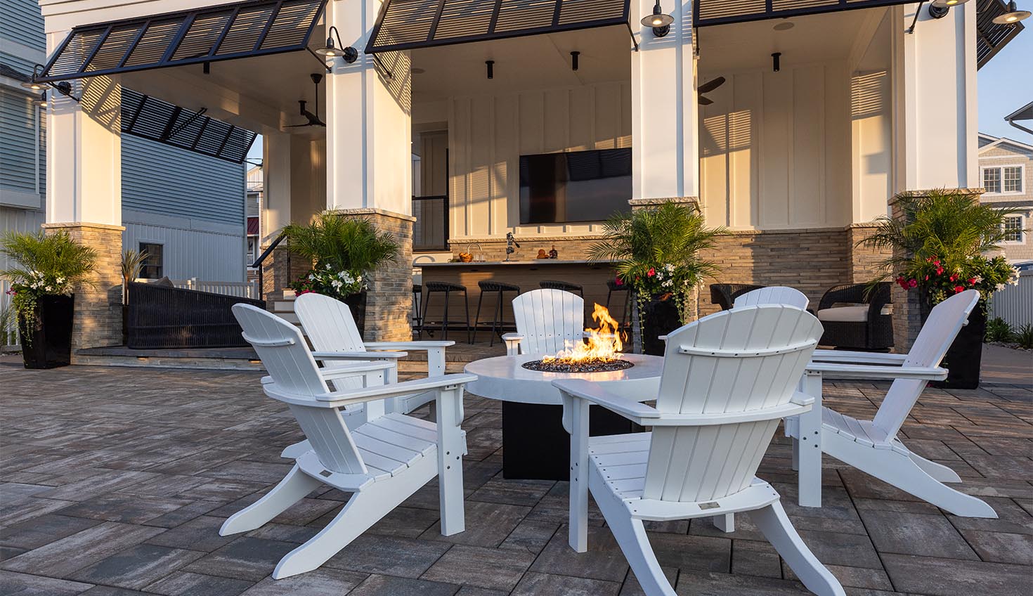 a patio with white chairs and a fire pit
