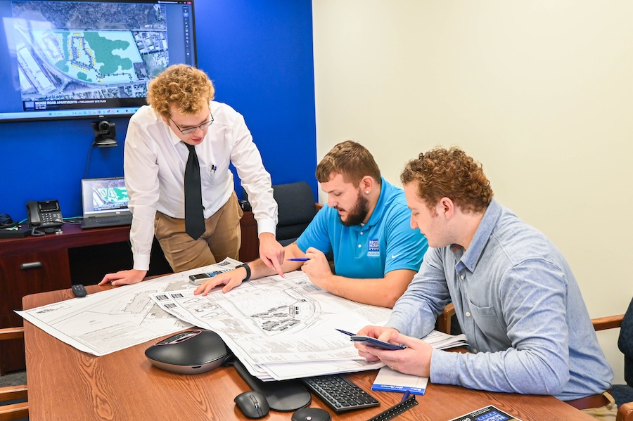 a group of men sitting around a table working on a project