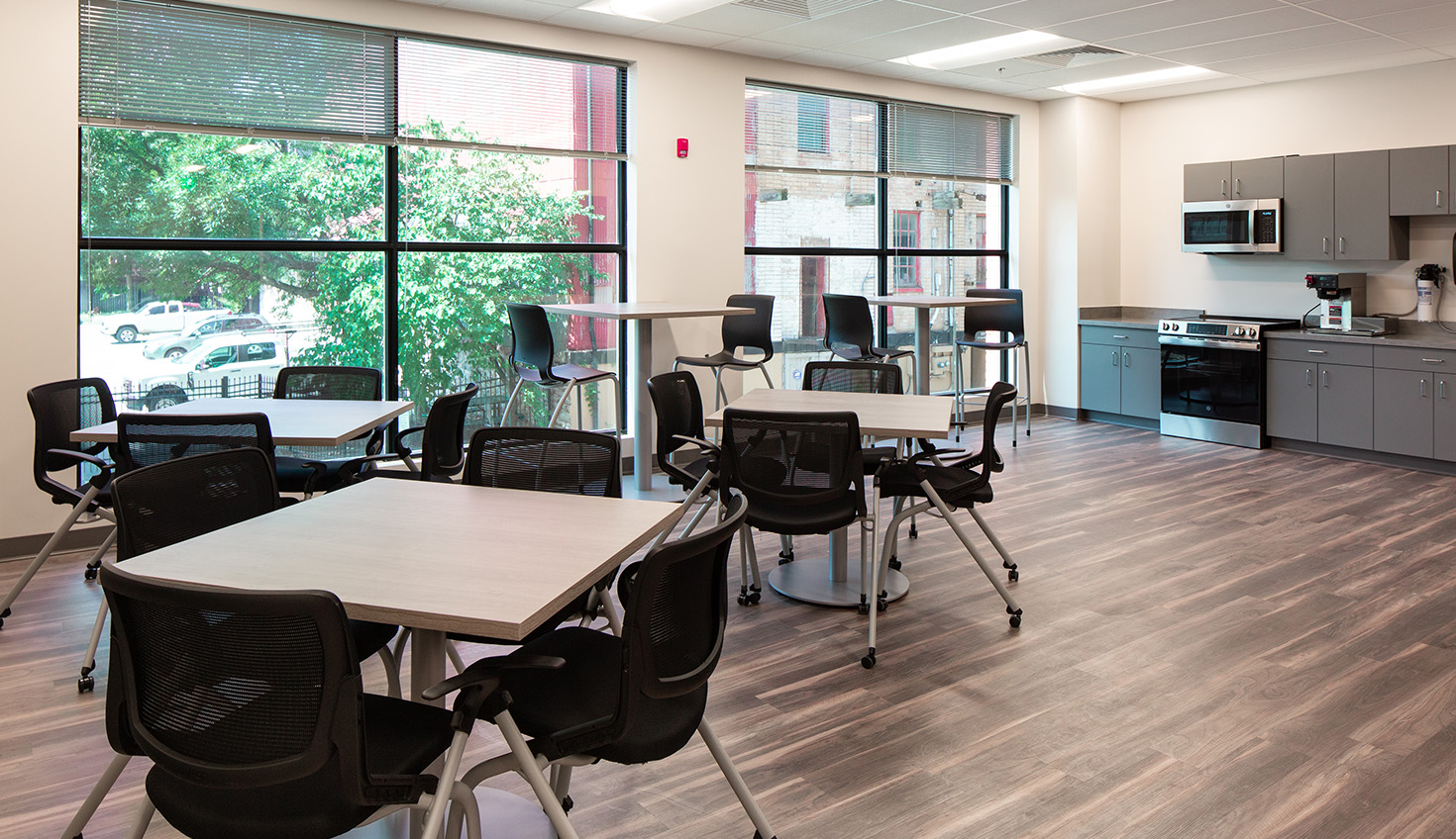 a room with tables, chairs, and a refrigerator